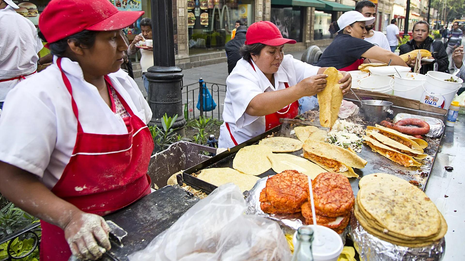 Vendors cooking tortillas, quesadillas and tacos on a street griddle in Mexico City's historic centre
