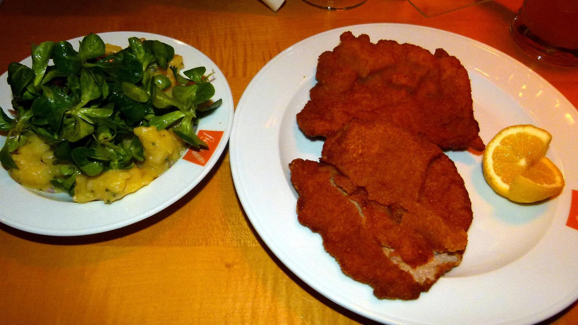 A golden schnitzel served with potato salad and lamb's lettuce at a Vienna restaurant